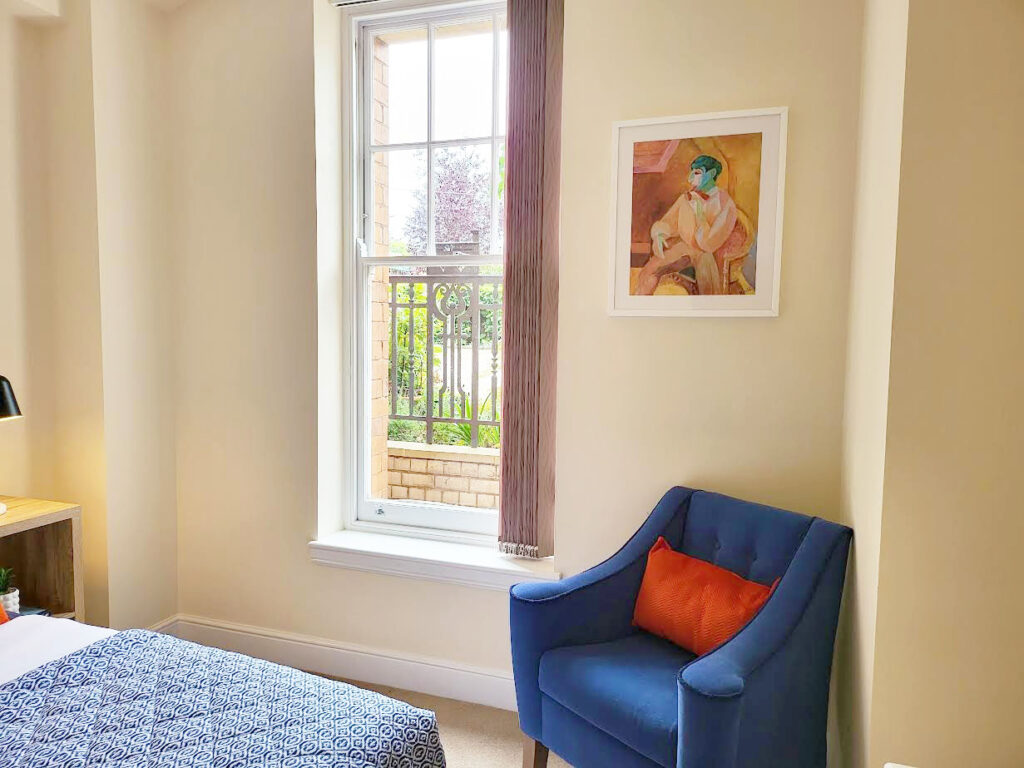 Image of guest bedroom in audley villages retirement apartment bed and accent chair in navy and orange colour scheme
