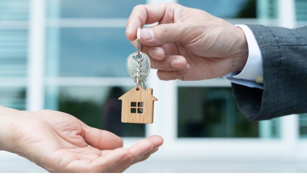 Estate agent and property owners handing over keys to a for sale property
