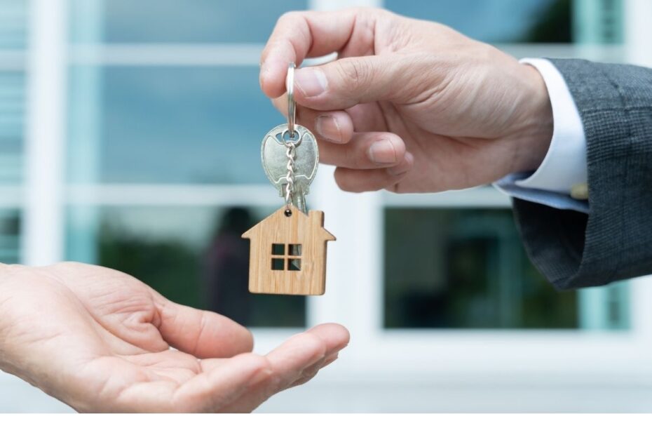Estate agent and property owners handing over keys to a for sale property